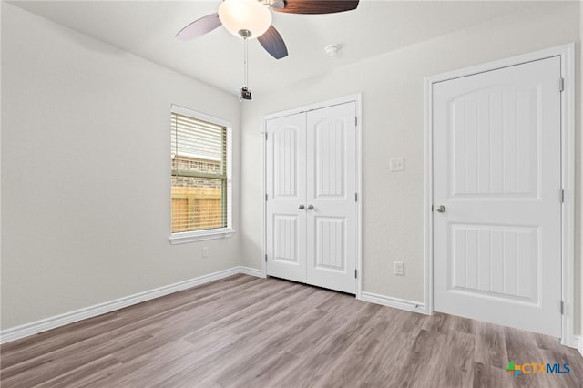 unfurnished bedroom with ceiling fan, a closet, light wood-type flooring, and baseboards