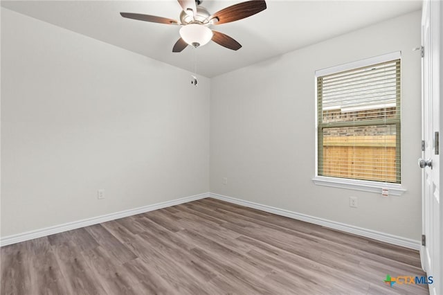 spare room featuring ceiling fan, light wood-style flooring, and baseboards