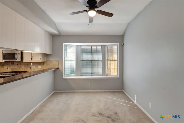 218 Sunset Dr, Victoria, TX 77901 - kitchen featuring appliances with stainless steel finishes, vaulted ceiling, backsplash, a ceiling fan, and dark countertops