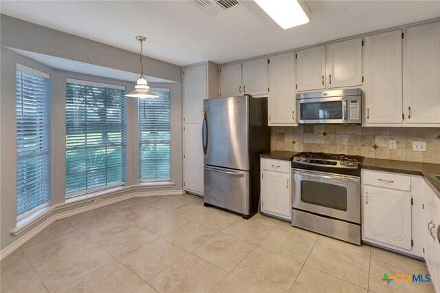 218 Sunset Dr, Victoria, TX 77901 - kitchen featuring stainless steel appliances, dark countertops, backsplash, light tile patterned flooring, and hanging light fixtures