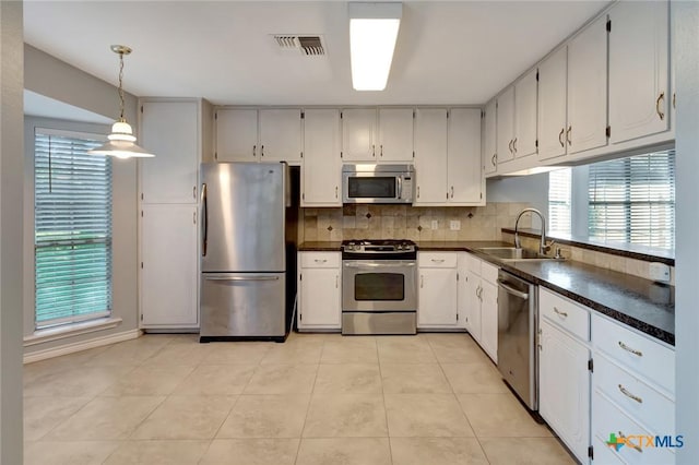 218 Sunset Dr, Victoria, TX 77901 - kitchen with stainless steel appliances, dark countertops, backsplash, and light tile patterned flooring