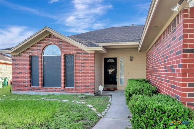218 Sunset Dr, Victoria, TX 77901 - property entrance featuring brick siding, roof with shingles, and a yard