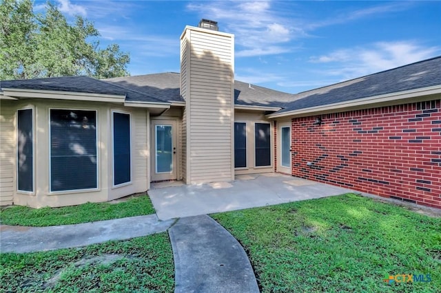 218 Sunset Dr, Victoria, TX 77901 - rear view of house with a chimney, a yard, a patio, and a shingled roof