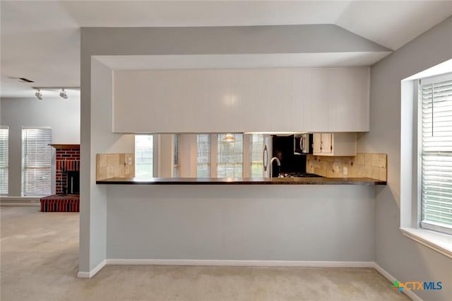 218 Sunset Dr, Victoria, TX 77901 - kitchen featuring carpet flooring, dark countertops, stainless steel microwave, and vaulted ceiling