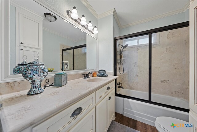 full bathroom featuring shower / bath combination with glass door, crown molding, vanity, hardwood / wood-style floors, and toilet