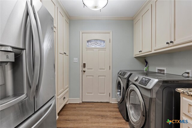 clothes washing area with light hardwood / wood-style flooring, cabinets, crown molding, and washing machine and clothes dryer