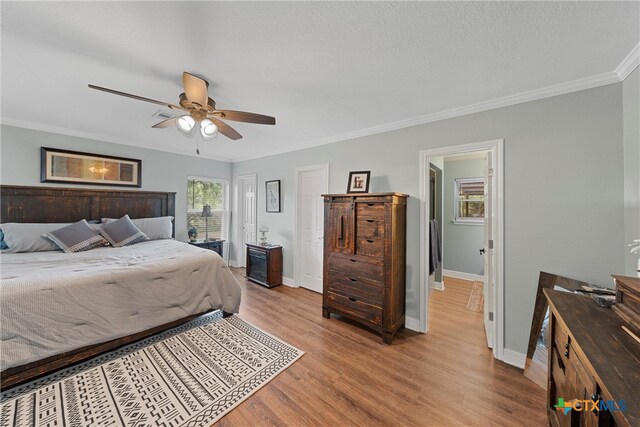 bedroom featuring ensuite bath, a textured ceiling, ceiling fan, crown molding, and light hardwood / wood-style flooring