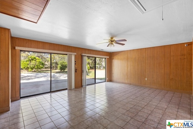 tiled empty room with wood walls and ceiling fan