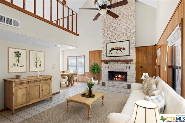 living room with a stone fireplace, wooden walls, and high vaulted ceiling