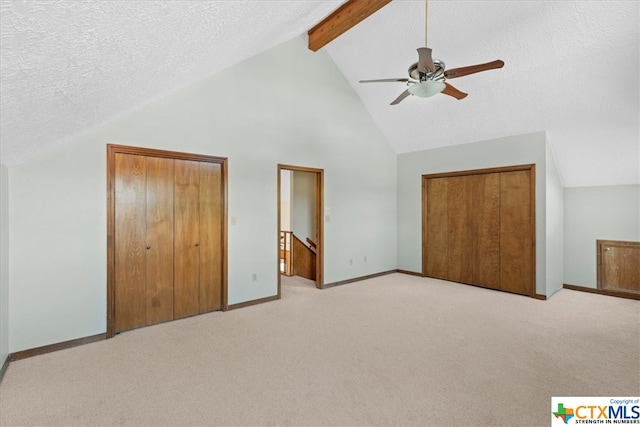 unfurnished bedroom featuring a textured ceiling, light colored carpet, ceiling fan, and beam ceiling