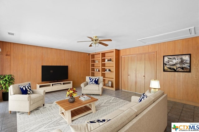 living room with wooden walls, light tile patterned floors, and ceiling fan