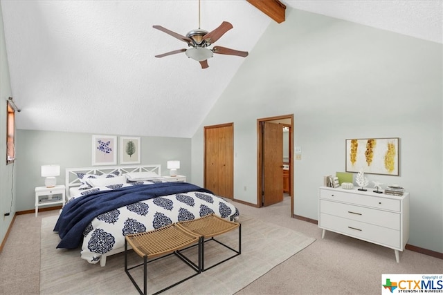 bedroom featuring ensuite bath, a textured ceiling, light carpet, beamed ceiling, and ceiling fan