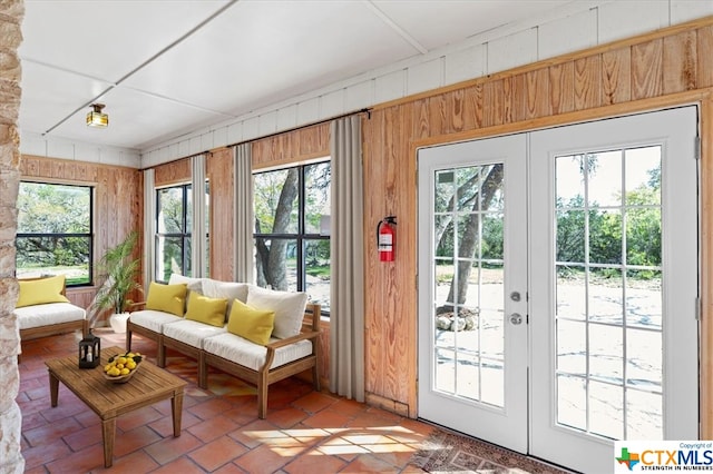 doorway to outside with wooden walls, a healthy amount of sunlight, and french doors