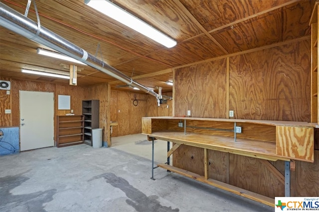 basement with a workshop area and wooden walls