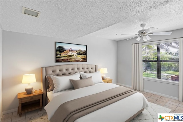 tiled bedroom featuring ceiling fan and a textured ceiling