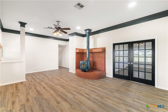 99 N Seakist Ln, Port Lavaca, TX 77979 - unfurnished living room with a wood stove, french doors, ceiling fan, ornamental molding, and wood finished floors