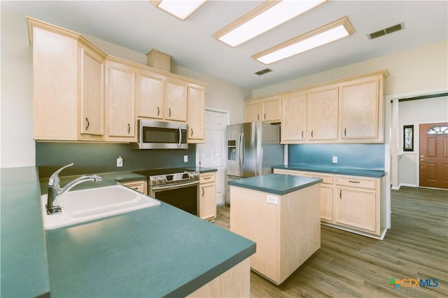 99 N Seakist Ln, Port Lavaca, TX 77979 - kitchen featuring appliances with stainless steel finishes, light brown cabinetry, dark countertops, and a kitchen island