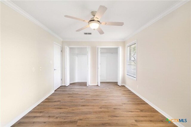 99 N Seakist Ln, Port Lavaca, TX 77979 - unfurnished bedroom featuring multiple closets, wood finished floors, ornamental molding, and a ceiling fan