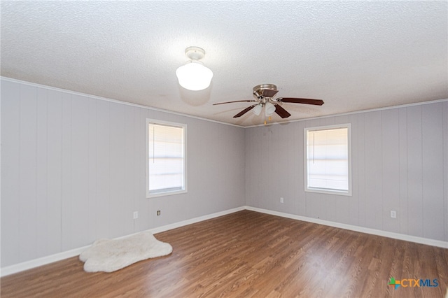 empty room featuring wooden walls, ceiling fan, wood-type flooring, and ornamental molding