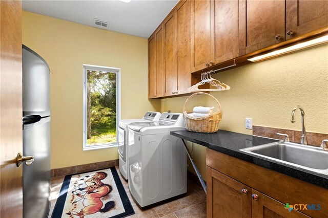 10329 Montanio Dr, New Braunfels, TX 78132 - laundry room featuring independent washer and dryer, cabinet space, tile patterned flooring, and arched walkways