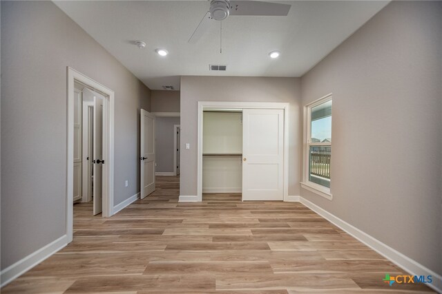 unfurnished bedroom featuring ceiling fan, a closet, and light wood-type flooring