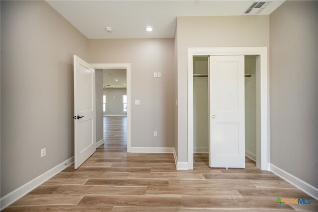 unfurnished bedroom featuring a closet and light hardwood / wood-style floors