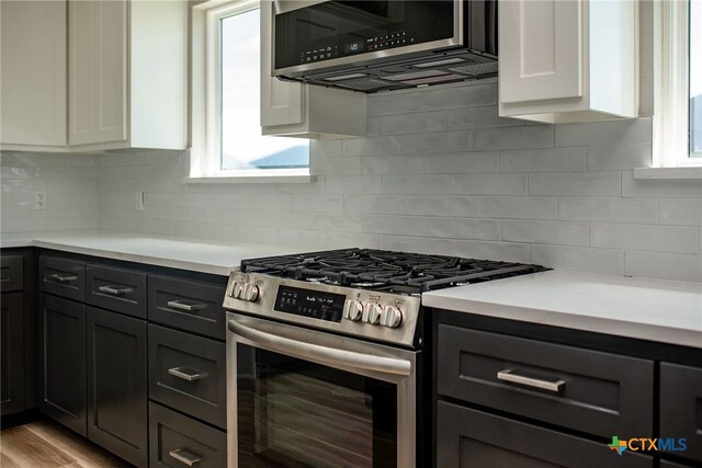 kitchen with tasteful backsplash, white cabinetry, light hardwood / wood-style floors, and stainless steel appliances