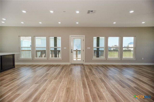 unfurnished living room with light wood-type flooring and a healthy amount of sunlight