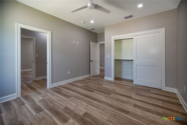 unfurnished bedroom with hardwood / wood-style floors, ceiling fan, and a closet