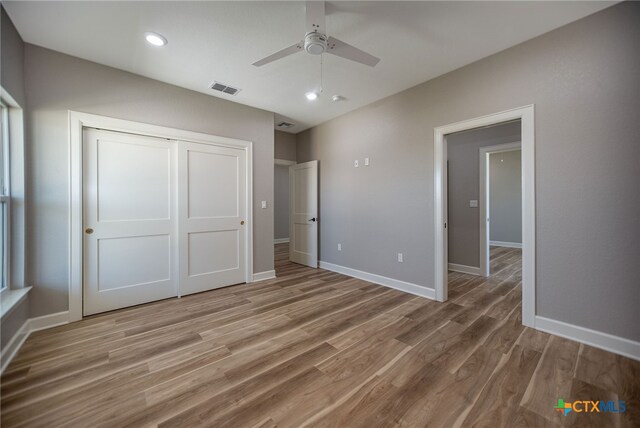 unfurnished bedroom featuring a closet, light hardwood / wood-style floors, and ceiling fan