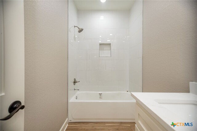 bathroom featuring wood-type flooring, vanity, and tiled shower / bath