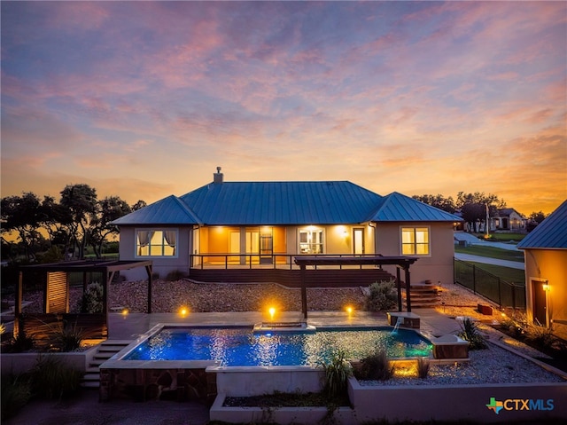 back house at dusk with a patio and pool water feature