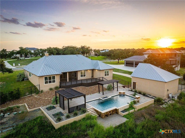 back house at dusk featuring a pool with hot tub and a patio area