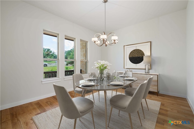 dining area with wood-type flooring and an inviting chandelier