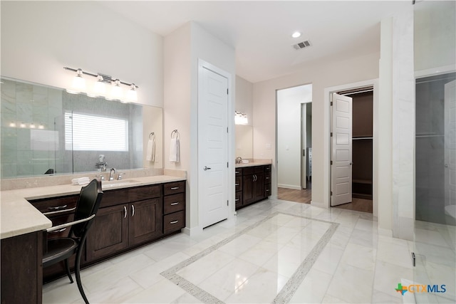 bathroom featuring a shower with shower door and vanity