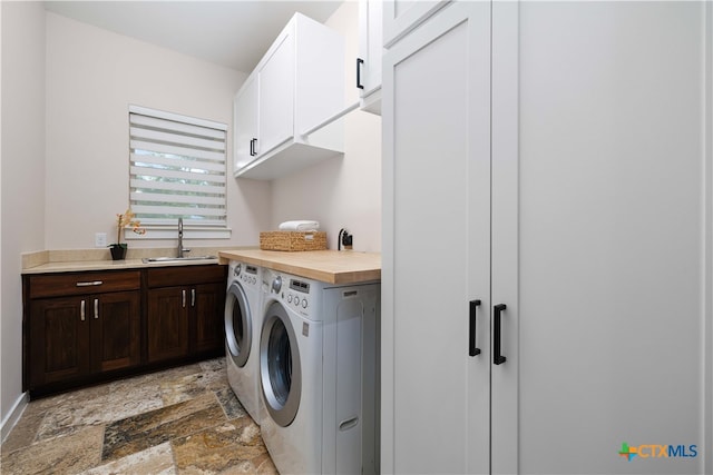 clothes washing area featuring washing machine and clothes dryer, cabinets, and sink