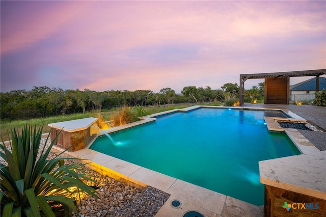 pool at dusk with a hot tub, a patio area, and pool water feature