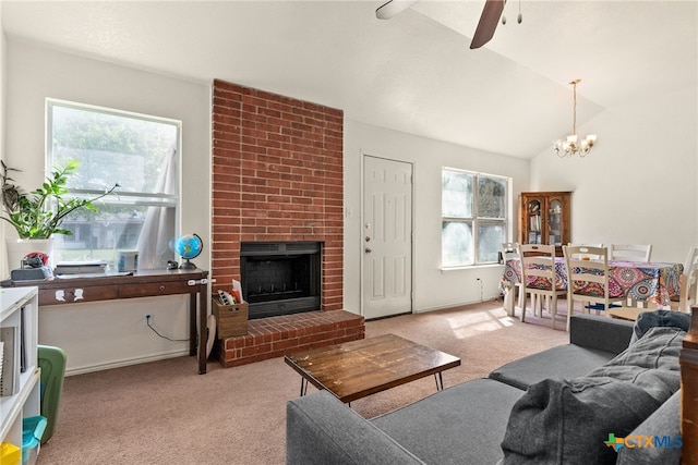 carpeted living room with a fireplace, ceiling fan with notable chandelier, and vaulted ceiling