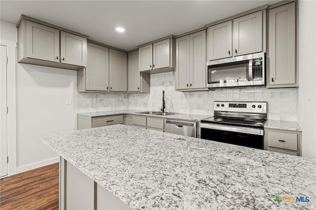 kitchen featuring backsplash, gray cabinetry, stainless steel appliances, dark wood-type flooring, and sink