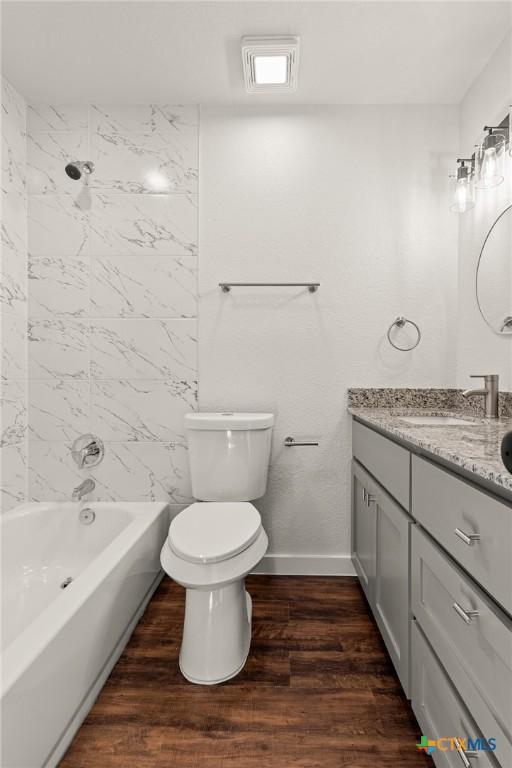 full bathroom with hardwood / wood-style floors, vanity, toilet, and tiled shower / bath