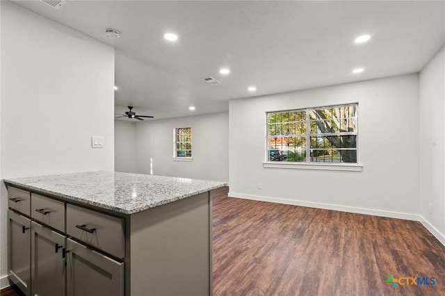 kitchen featuring gray cabinets, light stone counters, dark hardwood / wood-style flooring, and ceiling fan