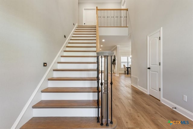 stairs featuring hardwood / wood-style floors and a high ceiling