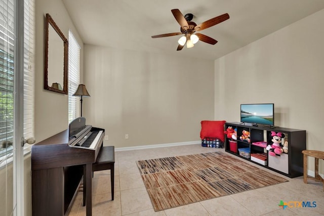 recreation room with tile patterned floors, baseboards, and ceiling fan