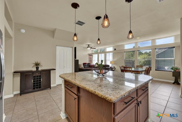 kitchen with light tile patterned floors, visible vents, brown cabinets, and hanging light fixtures