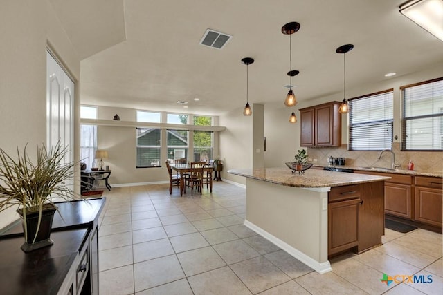kitchen featuring visible vents, backsplash, light tile patterned flooring, and a sink