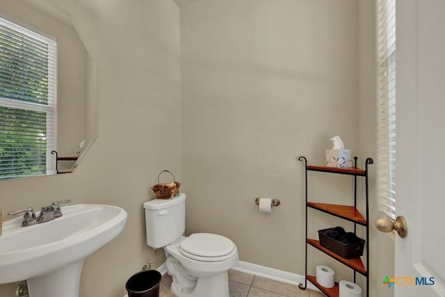 bathroom featuring toilet, tile patterned flooring, a sink, and baseboards