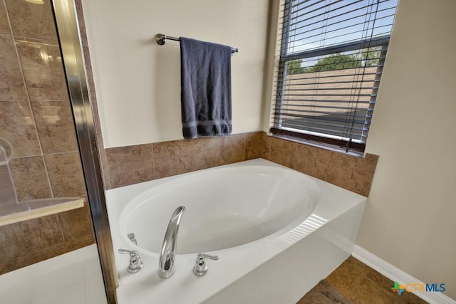bathroom with a garden tub, a tile shower, tile patterned floors, and baseboards