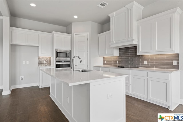 kitchen featuring sink, appliances with stainless steel finishes, an island with sink, white cabinets, and dark wood-type flooring