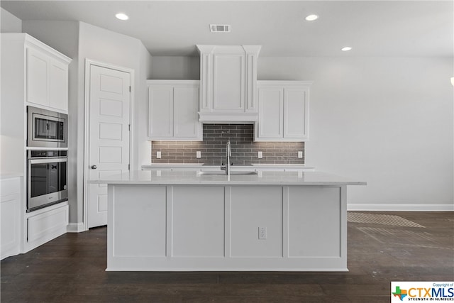 kitchen with stainless steel appliances, white cabinetry, an island with sink, and sink