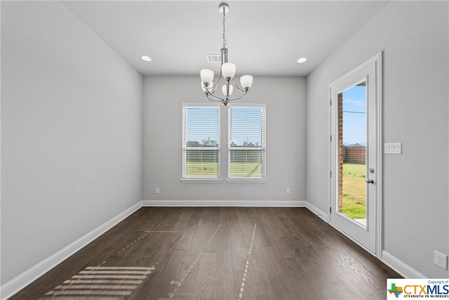 unfurnished dining area featuring dark wood-type flooring and a notable chandelier